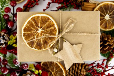 Ahşap yıldız ve kurutulmuş portakallı el sanatları hediye kutusunun yakın çekimi. Noel için çevre dostu ambalaj konsepti.