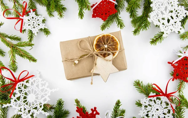 Gift in a craft box with eco decor, spruce branches and dried orange around.
