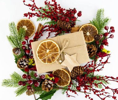 Noel kompozisyonu hediye kutusunda kurumuş portakal, ağaç yıldızı, çam kozalağı, ladin dalları ve kırmızı böğürtlenler var..