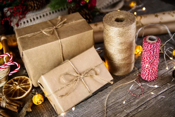 Gifts in craft paper and jute rope for Christmas on a wooden table.