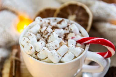 Kahveli, şekerli, lolipoplu beyaz bir fincan. Ekosenin etrafına, çelenk. Rahatlık konsepti, hygge.