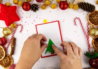Çocuklu bir Noel kartı için adım adım talimatlar. Renkli kağıt, yapıştırıcı ve makastan yapılmış bir kartpostalın üzerindeki ses ölçüsü ağaç. 4. Adım.