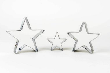 Beyaz arka planda farklı boyutlarda yıldız şeklinde üç metal kurabiye keskisi. Aile kavramı - anne, baba ve çocuk.