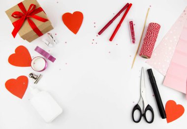 Sevgililer Günü. Tatil için kendi ellerinle kağıttan bir alt kanser yapıyorsun. Yukarıdan beyaz masaya bak, makas, kırmızı kalpler, hediye