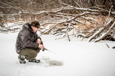Kışın balık. Bir adam kışın bir deliğin yanındaki buzda oturur ve küçük bir olta kamışı tutar. Bir balıkçı kışın balık tutar.