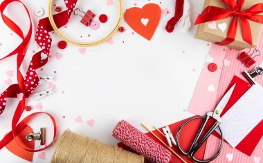 Sevgililer Günü geçmişi. Beyaz arka planda düz bir lei kırmızı kurdele, ataç, kalp, hediye, el işi..