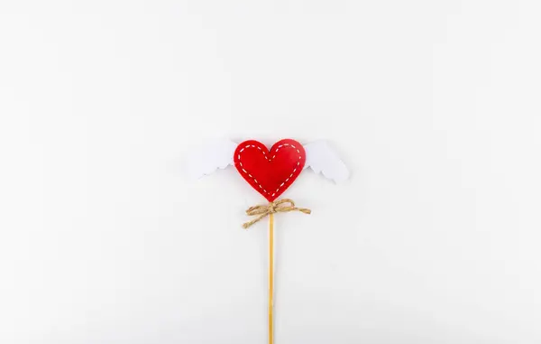 Heart with wings on a wooden stick on a white background in the center of the frame. Valentines Day background. — Stock Photo, Image