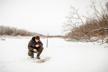 Kışın balık. Bir adam kışın bir deliğin yanındaki buzda oturur ve küçük bir olta kamışı tutar. Bir balıkçı kışın balık tutar.