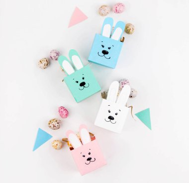 Renkli kağıtlardan Paskalya için çocuklarla el işi. Yumurta şeklinde tatlı olarak tavşanları kutular. Düz yatıyordu