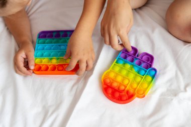 Çocuklar gökkuşağı pop oyuncağıyla oynarken eğleniyorlar.