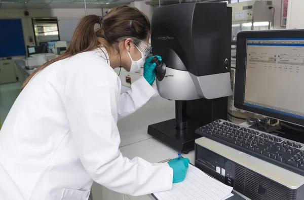 Mujer científica mirando a través del microscopio — Foto de Stock