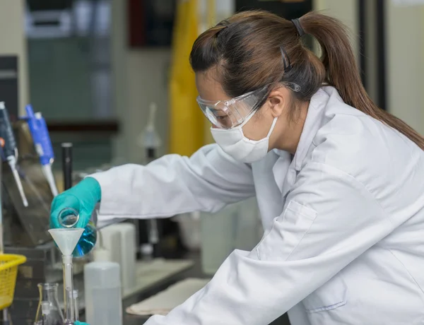 Mulher cientista enxaguando produtos químicos em vidro de teste — Fotografia de Stock