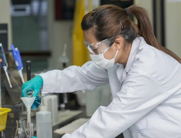 Женщина-ученый промывает химикаты в тестовое стекло Лицензионные Стоковые Фото