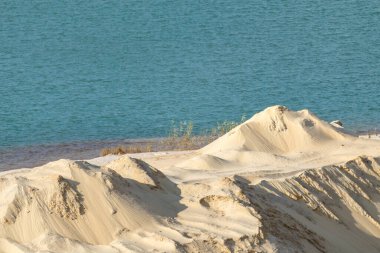 Sarı kum tepeleri ve mavi su doğal çöl arazisi. Taş ocağının dalgalı deseni