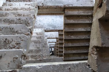 Terk edilmiş binanın içindeki tozlu beton merdiven. Bakış açısına göre tünel çok katlı.