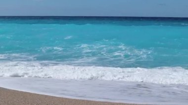 Yunanistan 'ın Lefkada adasının kıyısında, gök mavisi berrak ve berrak sularıyla çakıl taşlı plajda beyaz dalgalar var. Yaz vahşi doğa seyahati İyon Denizi 'ne