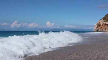 Yunanistan 'ın Lefkada adasının açık mavi sularıyla çakıl taşı plajında beyaz dalgalar yaklaşıyor. Yaz vahşi doğa seyahati İyon Denizi 'ne