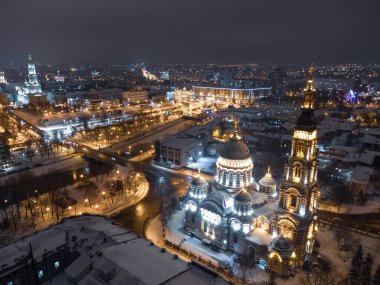 Kutsal Haber Katedrali kış karlı gece ışıklarıyla aydınlatıldı. Ukrayna nehir kıyısındaki Kharkiv şehri ortodoks kilisesi. Havadan yan görünüm.