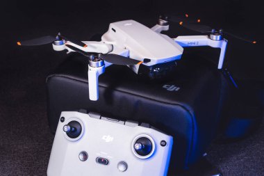 Kiev, Ukrayna - 02 Şubat 2021: Dji Mavic Mini 2 insansız hava aracı. Mavi ışıkta siyah arkaplanda uzaktan kumandalı siyah çanta üzerine yeni bir kuadkopter