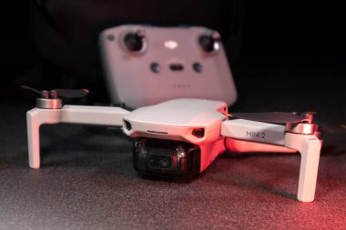 Kiev, Ukrayna - 02 Şubat 2021: Dji Mavic Mini 2 insansız hava aracı. Kırmızı ışıkta siyah arkaplan üzerinde uzaktan kumandalı yeni açılmış kuadkopter