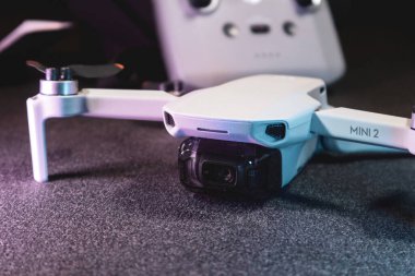 Kiev, Ukrayna - 02 Şubat 2021: Dji Mavic Mini 2 insansız hava aracı ön görüntüsü. Mor ışıkta siyah arkaplan üzerinde uzaktan kumandalı yeni açılmış kuadkopter