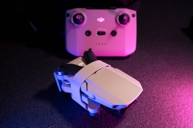 Kiev, Ukrayna - 02 Şubat 2021: Dji Mavic Mini 2 insansız hava aracı. Pembe ve mavi ışıkta siyah arkaplan üzerinde uzaktan kumandalı yeni katlanmış kuadkopter üst görünümü