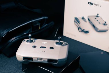 Kiev, Ukrayna - 02 Şubat 2021: Dji Mavic Mini 2 uzaktan kumandalı uzaktan kumandalı Bundle Fly More Combo çanta ve aksesuarları arka planda. Mavi renkte seçici odak