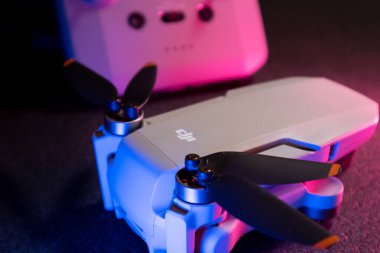 Kiev, Ukrayna - 02 Şubat 2021: Dji Mavic Mini 2 insansız hava aracı pervaneleri. Pembe ve mavi ışıkta siyah arkaplan üzerinde uzaktan kumandalı yeni kuadkopter