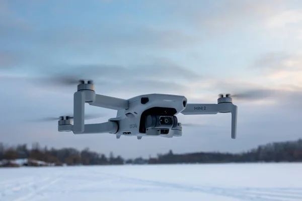 Kharkiv, Ukrayna - 21 Şubat 2021: Dji Maviç Mini 2, kış karlı havada gün batımı bulutlarında uçan insansız hava aracı. Pastel üzerinde gezinen yeni kuadkopter aygıtı bulanık arkaplan
