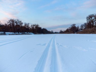 Akşamüstü mavi ışıkta ilerleyen karda kayak pisti çizgileri. Kışın aktif spor eğlencesi