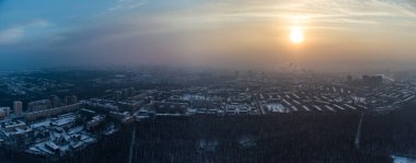 Hava manzaralı Kharkiv şehri Pavlove Pole bölgesi panoraması. Kış karanlık ormanlar, çok katlı evler ve karlı turuncu gün batımı gökyüzü