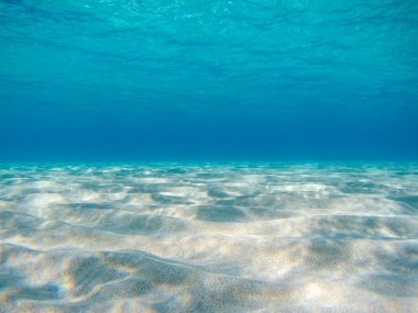Kum denizinin dibindeki su altı görüntüsü Yunanistan 'daki İyon Denizi' nin berrak sularında güneş ışığı yansımalarına yakın çekim yapıyor. Dalan gök mavisi vahşi deniz suyu