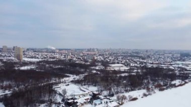 Lopan nehri üzerindeki Lugopark 'tan Kharkiv şehrine, şehir manzaralı Shevchenkivskyi ilçesine ve kışın manzaralı bulutlu gökyüzüne sahip çok katlı konutlu binalara hava sağından sol görüşü