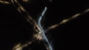 Yukarı uç ve gece üzerinde saat yönünün tersine dön aydınlanmış sokaklar ve yükseltilmiş metal köprü. Ukrayna 'nın Kharkiv kentindeki Botanik Bahçesi' nde hava manzarası