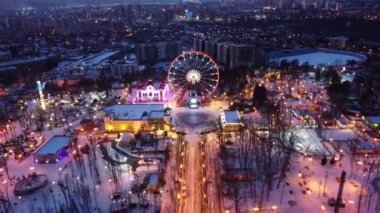 Aydınlatılmış dönme dolap üzerindeki hava manzarası ve gün batımında Gorky Central Park 'ın eğlencesi. Kışları Kharkiv 'de Dronie (uçup gider) görüntüleri. Şehir ışıkları, şehir manzarası