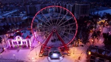 Havadan aydınlatılmış dönme dolap ve çekimler. Kışları Kharkiv şehrinde Dronie (uçup gider) görüntüleri. Gün batımında eğlence Gorky Central Park. Şehir ışıkları
