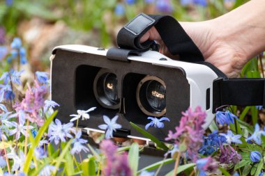 3D sanal gerçeklik gözlüklü, ön tarafı mor ve mavi renkli kır çiçekleriyle açılmış bir gözlük. VR teknoloji ekipman gözlükleri yakın plan.