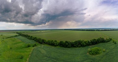 Gökyüzü manzarası, fırtınalı bulutlu yeşil alanlar üzerinde uçmak. Kırsal kesimde koyu yağmurlu ve ağır bir hava var. Drone görünümü
