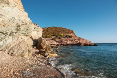 Vahşi Akdeniz çakıl taşlı plajı kayalık kayalıklar kıyıları ve mavi berrak su ile yakın çekim. Atina yakınlarında Yunanistan 'ı gezmek. Yaz doğası manzaralı göl