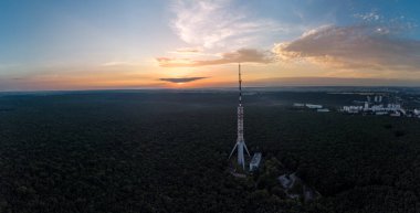 Telekomünikasyon kulesi antenli ve şafak bulutlu gökyüzü manzaralı, havadan gündoğumlu yaz panoramik manzarası. Kharkiv, Ukrayna