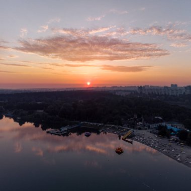 Geniş nehir üzerinde yansıyan su yüzeyine yansıyan bulutların olduğu manzaralı hava gündoğumu. Kumsalın üstünde sabahın erken saatlerinde, Kharkiv Zhuravlivsky Hidropark 'ta gökyüzünden şafak sökerken. Drone fotoğrafçılığı