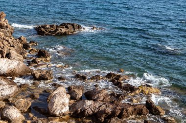 Akdeniz kıyısındaki vahşi kayalar ve mavi berrak su. Yunanistan 'ın doğal varış noktalarını dolaş. Yaz doğası manzaralı sahil