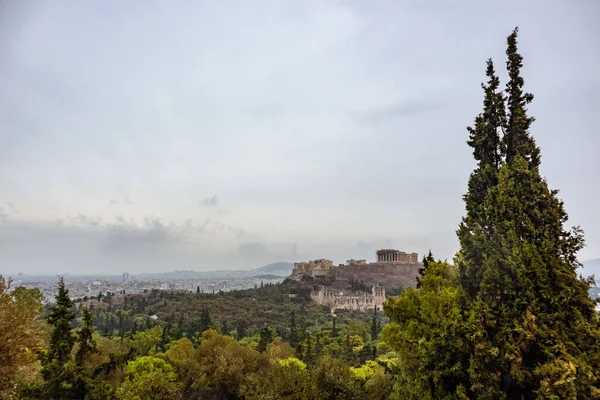 雅典卫城山 Parthenon Propylaea Temples Odeon Herode Atticus 以及从绿树成荫的白色城市景观 阴天从Filopappou Hill到雅典的古老历史遗迹 — 图库照片
