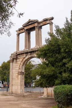 Atina, Yunanistan - 24 Eylül 2019: Hadrian Kemeri, Hadrian Kapısı, yeşil ağaçlı antik bir kapı. Antik şehir merkezinde Roma zafer kemeri. Dikey