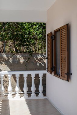 Klasik Yunan mimarisi beyaz teras balkonlu balkon ve pencereli panjurlu. Gölgedeki yeşilliğe bak. Yunanistan, Atina yakınlarındaki kır evinde yaz mevsimi. Dikey görünüm