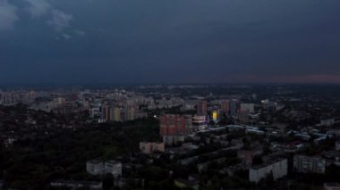 Şehir üzerinde soldan sağa doğru hava aksamı bulutlu dramatik ağır günbatımı gökyüzü ile. Şehir sokaklarının üzerinde akşam uçuşu. Kharkiv, Ukrayna şehir merkezi parkı ve yerleşim bölgesi