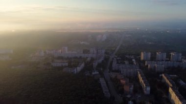 Şehirde gün doğumu, destansı bulutlar, sis ve güneş parlıyor. Sabahın erken saatlerinde uyuyan şehrin üzerinde. Sağdan sola panoramik görünüm