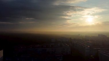 Şehirde gün doğumu, destansı bulutlar, sis ve güneş parlıyor. Sabahın erken saatlerinde uyuyan şehrin üzerinde. Panoramik görünümle uç