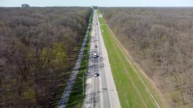 Güneşli bir bahar gününde ormanın yakınında bisiklet yolu ile havadan ön tarafa uçuyor. Yukarıdan arabalarla asfalt yolda bisikletleri ayırın.