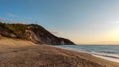 Sıcak yaz günbatımında, Yunanistan 'ın Lefkada adasının yüksek kayalıklarıyla kıyıda Mylos kumsalında. İyon Denizi 'ne yaz seyahati. Panorama görünümü